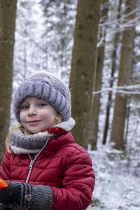 Portrait of smiling boy standing on snow covered field