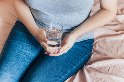 Woman sits in bed and holds glass of clean water in her hands. world water day. health care concept.