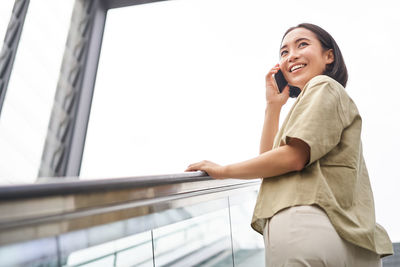 Portrait of young woman standing against railing