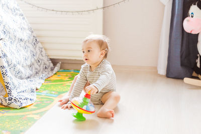 Cute boy playing with toy sitting on floor