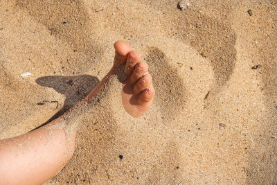 High angle view of hands on sand