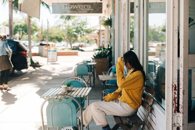 Side view of woman sitting at sidewalk cafe