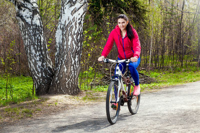 Young beautiful woman is walking in the spring forest on a bicycle
