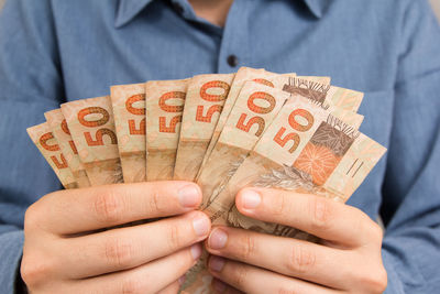 Close-up of man holding paper currencies in envelope