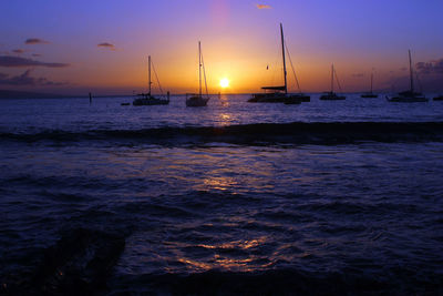 Sailboats in sea against sky during sunset
