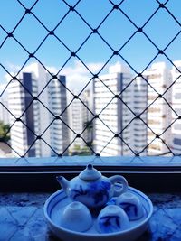 Close-up of blue glass with metal fence and table