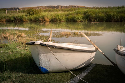 Boat moored on shore by lake