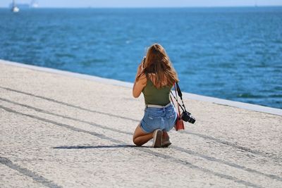 Woman kneeling at beach in city