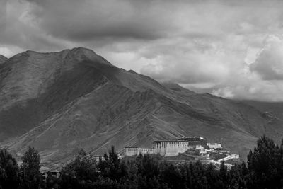 Potala palace by mountains against cloudy sky