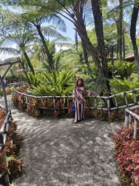 Full length portrait of woman standing on palm trees