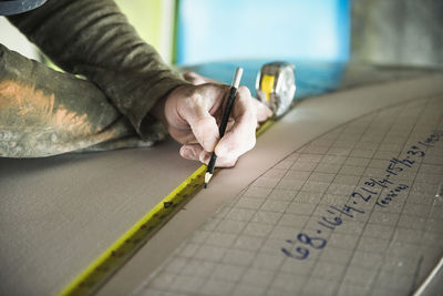 Surfboard shaper measuring a new design