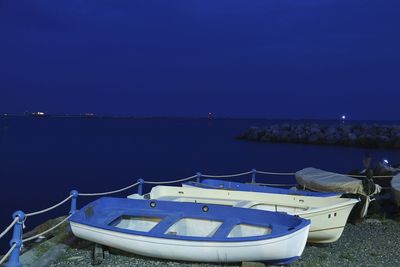 Boats moored on sea against clear blue sky