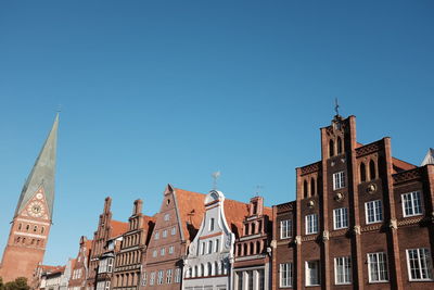 Low angle view of church and residential buildings against clear blue sky