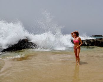 Portrait of young woman splashing water at beach