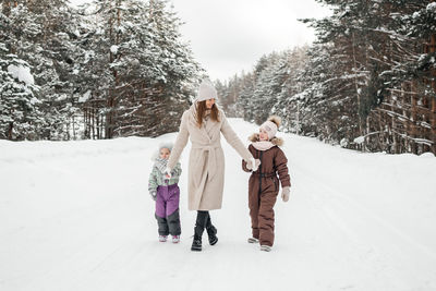 Mother with two daughters walks in a snowy forest on her day off. high quality photo