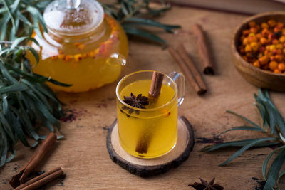 Autumn tea in a sea buckthorn mug with a cinnamon stick on a wooden background. autumn mood.