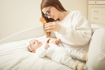 Mother plays with newborn baby, little girl explores world, looks at toy. early development, 