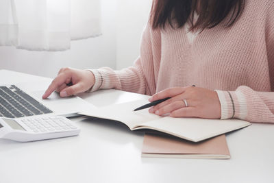 Midsection of woman reading book on table