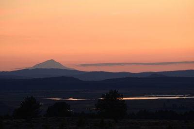 Scenic view of silhouette mountains against orange sky