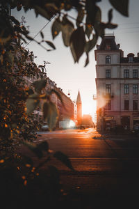 Road amidst buildings against sky during sunset