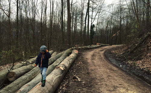 Kid walking on log in forest