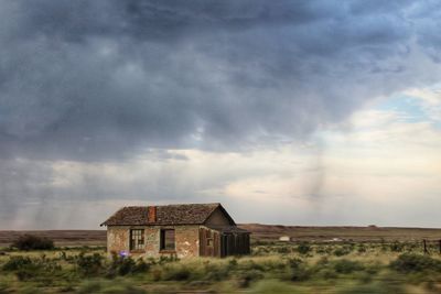 Abandoned house on field against sky in a stormy day. in the middle of nowhere