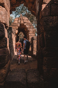 Rear view of couple holding hands while walking in old ruins