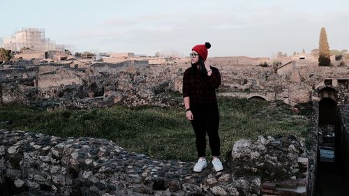 Full length of woman standing on retaining wall against sky