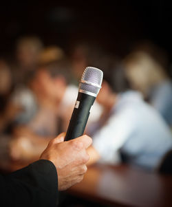 Cropped hand of male public speaker holding microphone in lecture hall