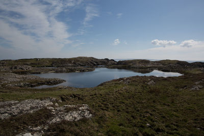 Scenic view of lake amidst mossy landscape against blue sky