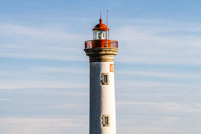 Lighthouse by building against sky