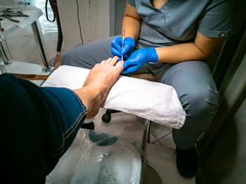 Gloved master makes a pedicure for a client. close-up no face. woman in nail salon paints her nails