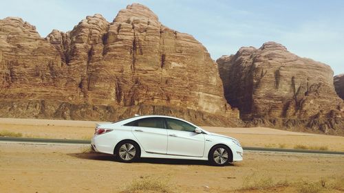 Vintage car on rock formation against mountain