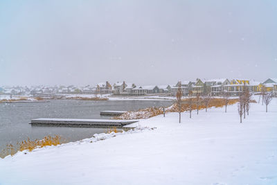 Scenic view of frozen river by buildings against sky