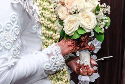 Midsection of bride holding rose bouquet