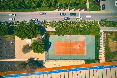 Roadside tennis court. top down aerial view of tennis court and cars on a city street
