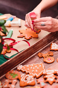 Cropped hands of woman preparing gingerbread cookies on cutting board