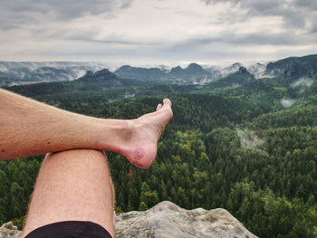 Midsection of person wearing hat on mountain against sky