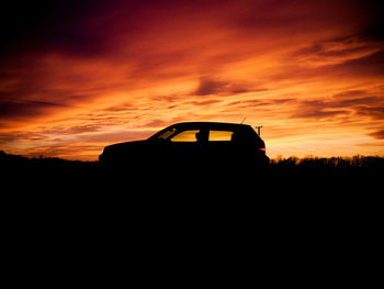 Silhouette car on field against sky during sunset