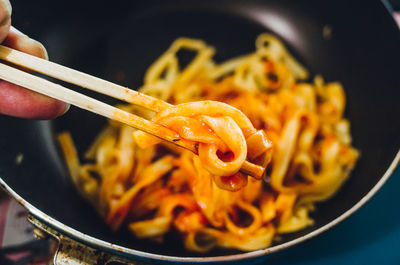 Cropped hand having pasta on table