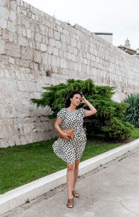 Full length of woman standing against wall