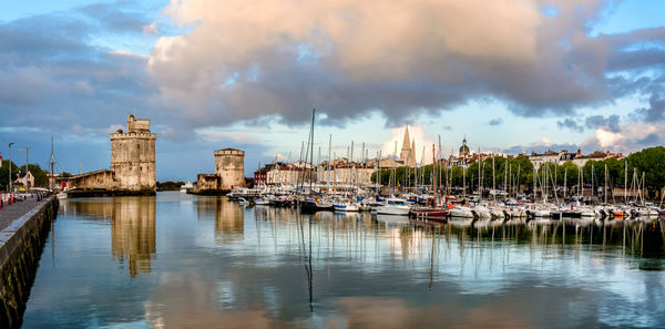 Sailboats moored in harbor against buildings in city