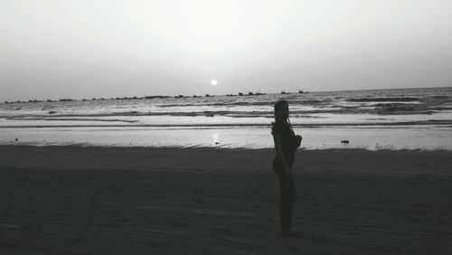 Woman standing on beach against clear sky