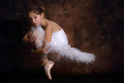 Full length portrait of ballet dancing against wall