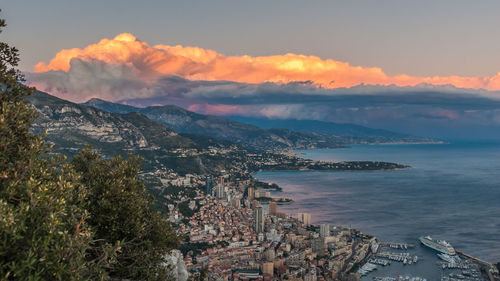 Cityscape by sea against cloudy sky sunset