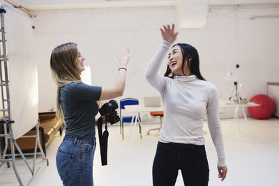 Cheerful female bloggers giving high-five at creative office