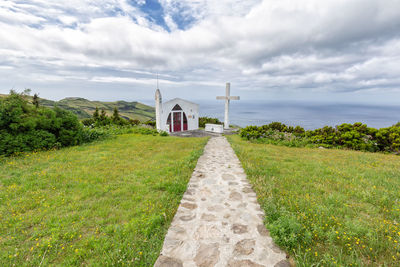 Footpath leading towards temple against sky