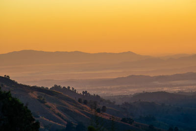 Scenic view of silhouette mountains against orange sky