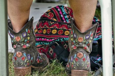 Two legs in printed  boots shot from behind with a colorful purse 