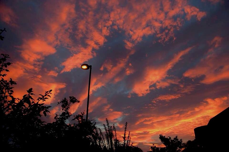 sunset, sky, silhouette, cloud - sky, low angle view, orange color, dramatic sky, beauty in nature, cloudy, scenics, tree, cloud, nature, tranquility, tranquil scene, built structure, idyllic, overcast, moody sky, building exterior